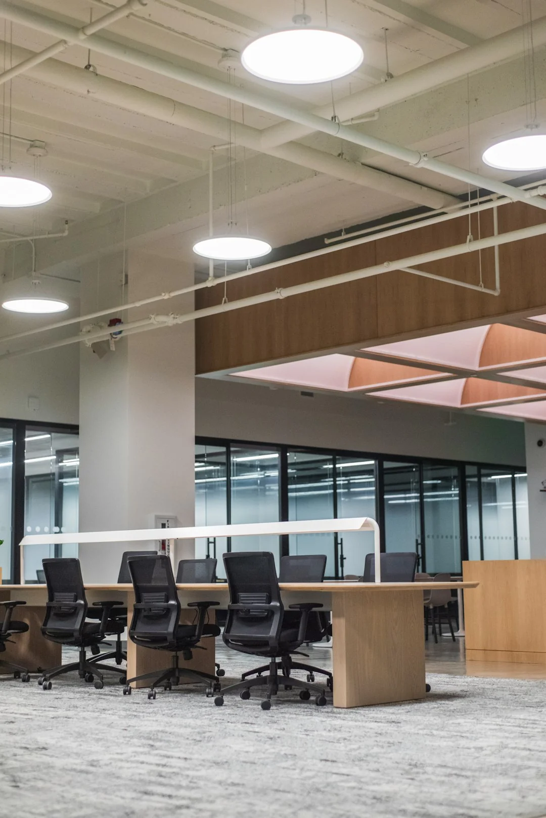 Spacious and contemporary office interior with glass partitions, stylish furniture, and vibrant wall art.